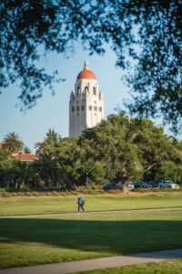 Captivating view of Hoover Tower at Stanford University framed by trees and a vibrant park.